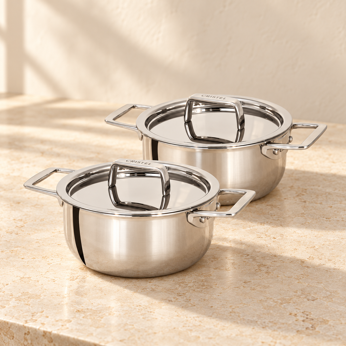 Set of 2 Mini Stewpans With Lid by CRISTEL USA on a warm limestone counter