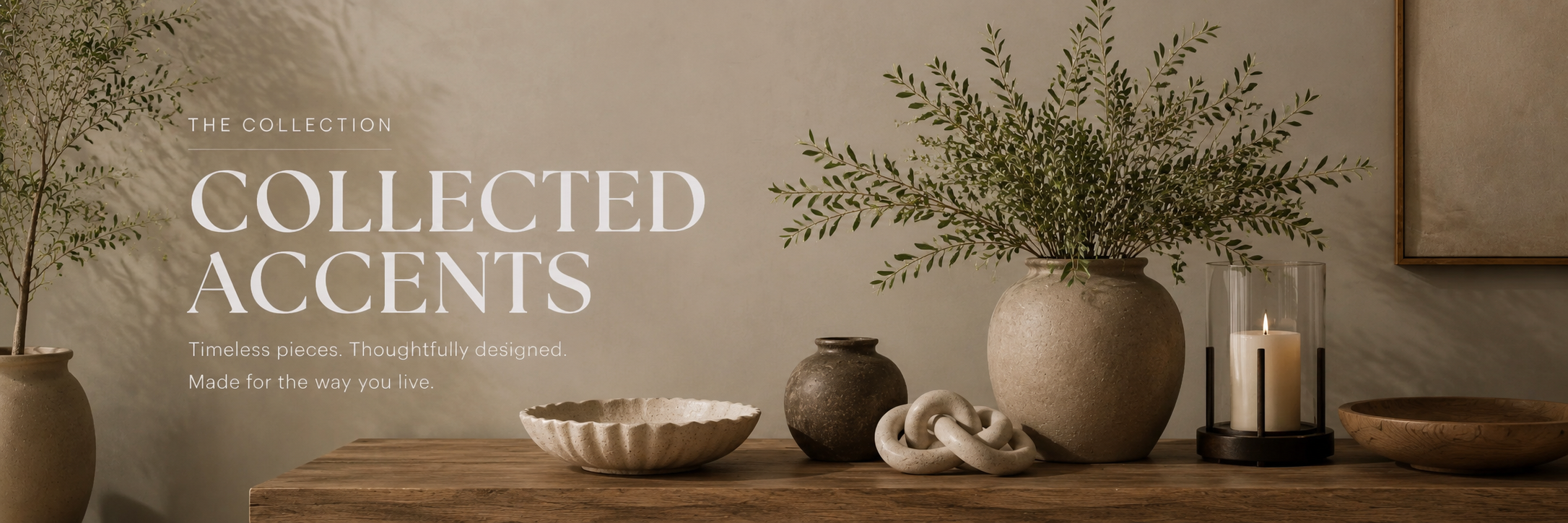 Neutral decorative accents styled on a wood console with ceramics, books, greenery, and a candle in a warm, refined home setting