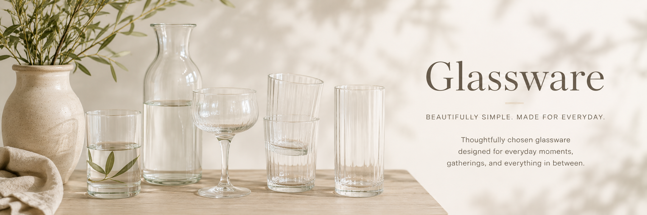 Minimal neutral glassware collection with carafe, drinking glasses, and soft editorial kitchen styling