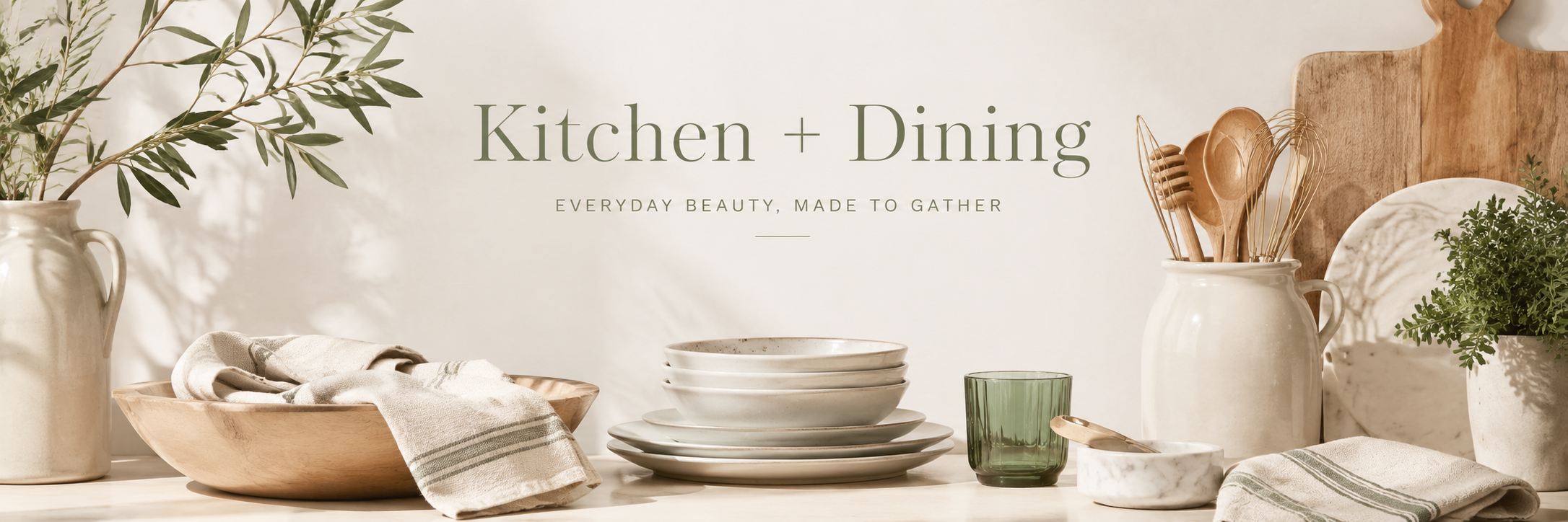 Neutral kitchen and dining decor with dishes, wood utensils, and green accents styled in a light refined space