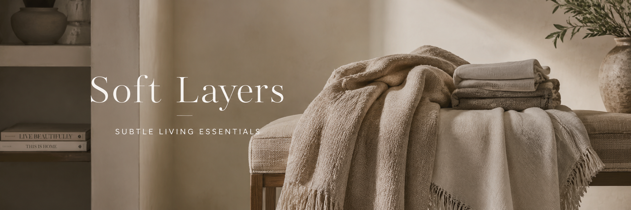Neutral throw blankets layered on a bench in a warm, refined living space