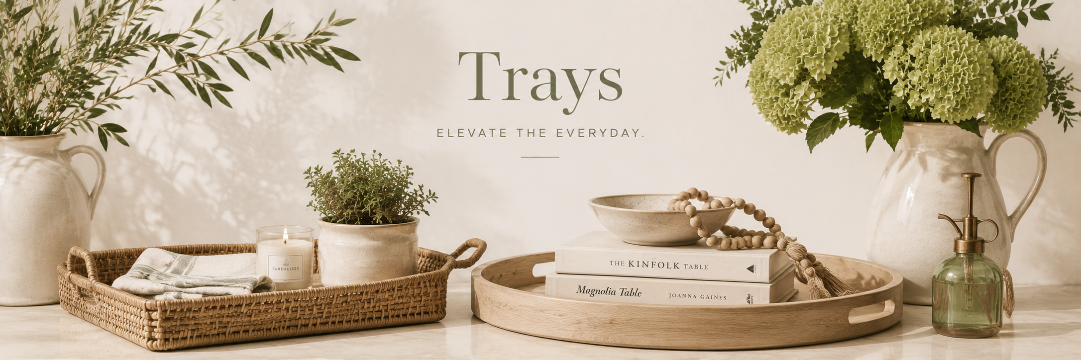 Neutral decorative trays styled with candles, books, and greenery in a warm, refined home setting