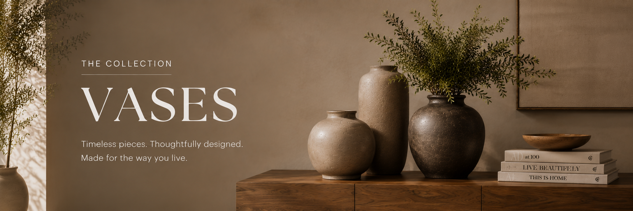 Collection of neutral-toned ceramic vases in varying shapes displayed on a wooden console with greenery and stacked books