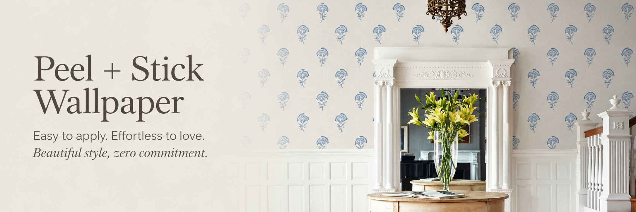 Peel and stick wallpaper banner featuring a refined entryway with blue floral wallpaper, white wainscoting, an ornate doorway, and a wooden table with fresh flowers.