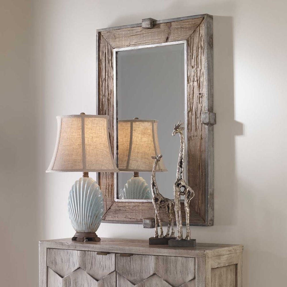 Wood mirror styled above a cabinet with a lamp